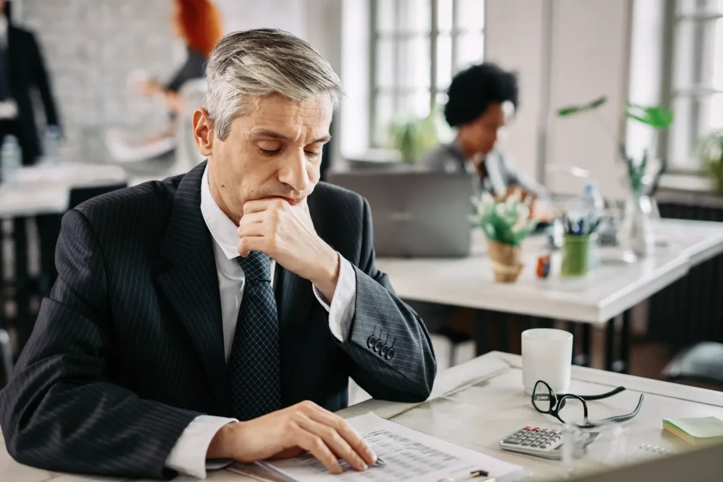 thoughtful businessman sitting desk office going through financial reports